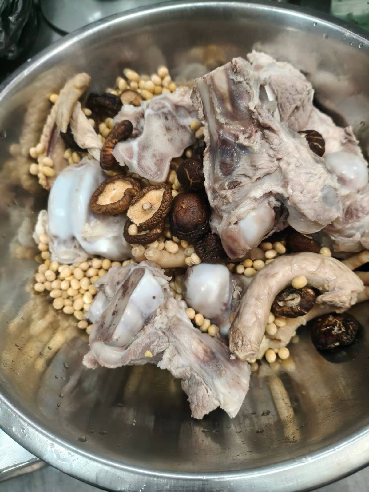 Raw bone-stock ingredients — chicken, pork bones, soybeans, and dried shiitake — before simmering.